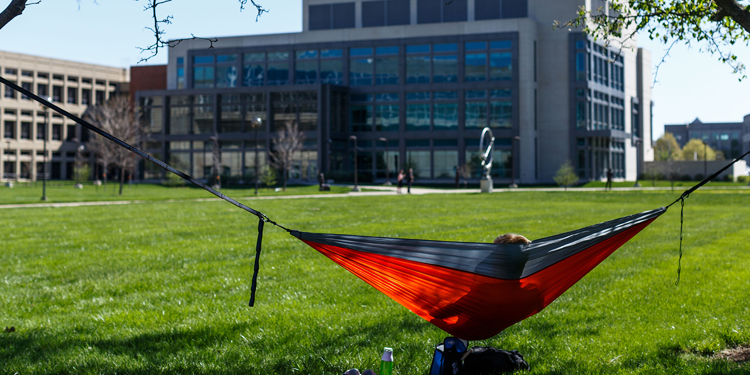 Student sits in a hammock in the south meadow.